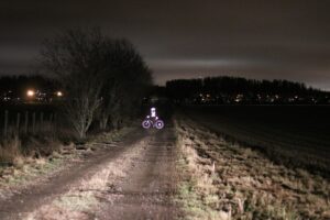 Pimeä pyöräily - pyörä auton ajovaloissa