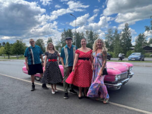 Someryhmä poseeraamassa Anitan kanssa pinkin Cadillacin edessä