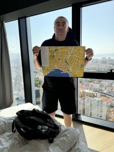 Ilkka esittelee Splitin karttaa AC Hotel Splitin huoneessa ikkunan edessä.